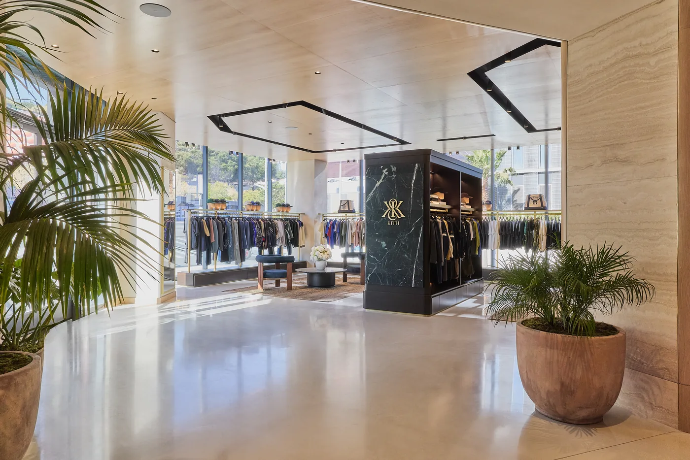 The entrance hall at KITH West Hollywood, the brand monogram set behind a palm and a low display plinth